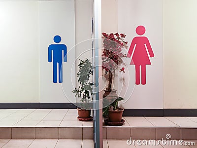 Toilet entrance with restroom sign with blue silhouette man symbol and red silhouette woman symbol Stock Photo