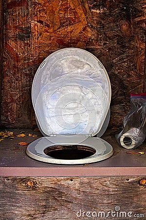 A toilet seat and paper in an outhouse Stock Photo