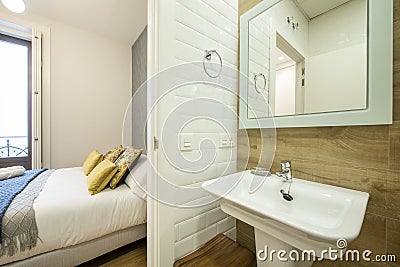 Toilet with white sink and mirror next to a king size bed in a modern vacation Stock Photo