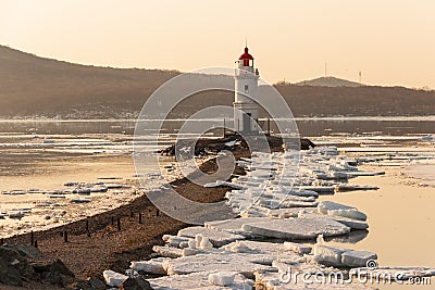 Tokarevsky lighthouse on the Egersheld peninsula in Vladivostok on a winter morning at dawn among ice floes floating in the sea Stock Photo