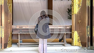 TOKYO, JAPAN - APRIL, 10, 2018: a female japanese worshiper prays at meiji shrine in tokyo Editorial Stock Photo