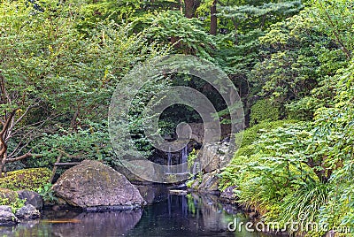 Small waterfall in the pond of the Japanese Garden of Hotel New Otani. Stock Photo