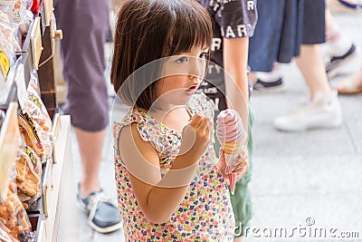 Tokyo, Japan - 13 June 2015 - Young little Asian girl enjoy her soft ice cream outside of a snack shop in Tokyo, Japan on June 13 Editorial Stock Photo