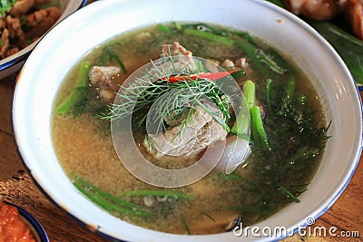 Tom sab cartilage soup delicious Thai Esan dish in white bowl on wooden table. Stock Photo