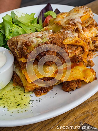 Tomato and beef lasagne with cheese layered between sheets of traditional Italian pasta served on a white plate on a restaurant or Stock Photo