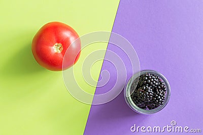 Tomato and blackberry on a green-purple background Stock Photo