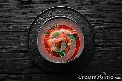 Tomato cream soup with shrimps in a black bowl. Seafood menu. Stock Photo