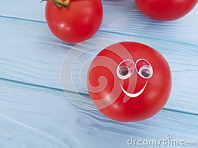Tomato funny organic ingredient nature concept person eyes cartoon on blue wooden positive emotion Stock Photo