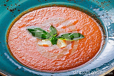 Tomato gazpacho soup with basil, feta cheese, ice and bread on dark wooden background, Spanish cuisine. Ingredients on table. Top Stock Photo