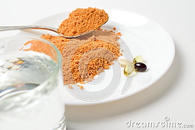 Tomato protein soup powder on a spoon. Meal replacement. Dry soup. Multivitamins, astaxanthin, fish oil, omega pills on a plate. Stock Photo