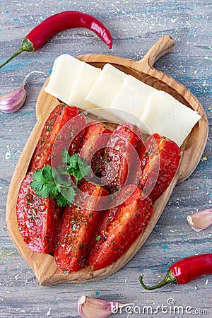 Tomato salad with hot peppers, olive oil and cheese on wooden plate Stock Photo