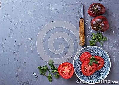 Tomato, salt, parsley and knife on gray concrete background Stock Photo