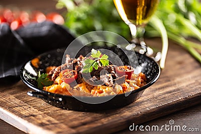 Tomato sauce gnocchi with sous-vide beef and fresh tomatoes served in a dark plate Stock Photo