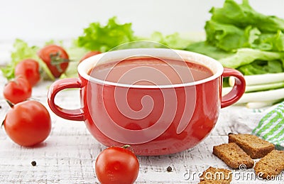 Tomato soup in red ceramic bowl on rustic wooden background. Hea Stock Photo