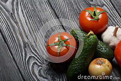 Tomatoes with green ponytails, onion and garlic head. Two green prickly cucumbers with yellow flowers. They lie on the surface of Stock Photo