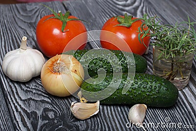 Tomatoes with green ponytails, onion, lemon and garlic head. Two green prickly cucumbers with yellow flowers. A glass with Stock Photo