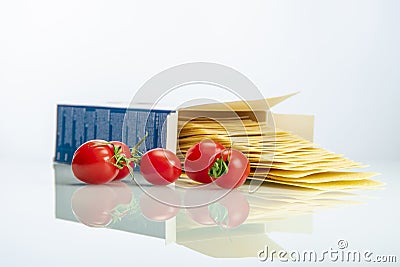 Tomatoes with lasagna on white reflexive glass Stock Photo