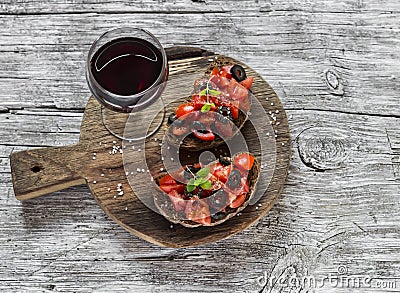 Tomatoes and olives bruschetta and a glass of red wine on rustic background Stock Photo