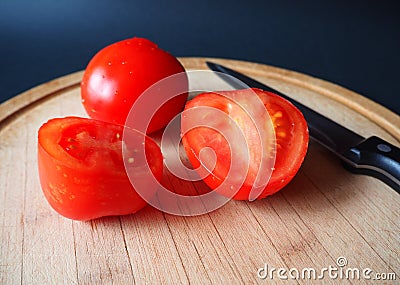 Tomatoes on the round wooden cutting board with a knife Stock Photo