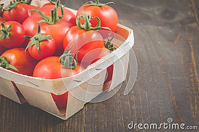 Tomatoes in a wattled basket/tomatoes in a wattled container on a dark wooden background, selective focus and copyspace Stock Photo
