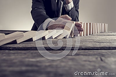 Toned image of a businessman stopping domino effect Stock Photo