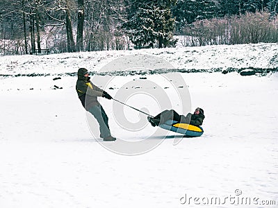 Toned image of a happy family where dad lucky sledging laughing little boy in a forest of fir trees Stock Photo