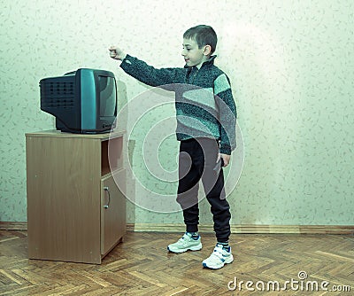 Toned image of a little boy with a disappointed face which is holding the TV remote Stock Photo