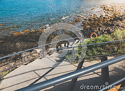 Toned image of curved stairs with handrails on the ocean coast with sharp cliffs Stock Photo