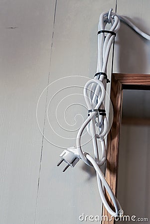 A too long powercord hanging on a bathroom wall next to a..mirror Stock Photo
