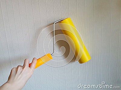 Tool, roller for smoothing wallpaper yellow. Paint roller with a red handle and a yellow smooth nozzle on a light background. Stock Photo