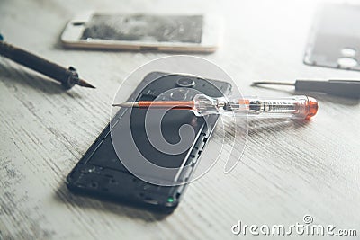 Tools with broken phones on table Stock Photo