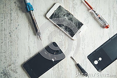 Tools with broken phones on table Stock Photo