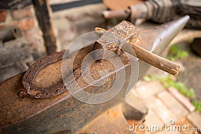 Tools in an old blacksmith& x27;s workshop. Horseshoe and hammer on a large anvil Stock Photo