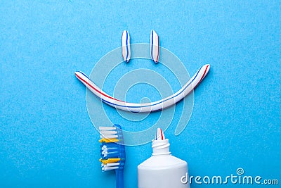 Tooth-paste in the form of a face with smile. Tube of toothpaste and toothbrush on a blue background Stock Photo