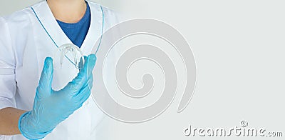 Tooth whitening, a tooth mold in doctors hand. Dental beauty treatment. Teeth retaining tools after braces. Concept Orthodontics Stock Photo