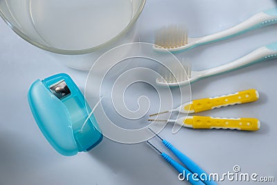 Toothbrushes, dental floss, interdental brushes and a glass of medicated mouthwash on white background Stock Photo