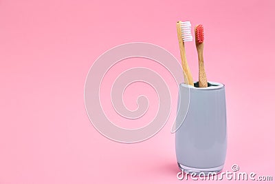 Toothbrushes made of bamboo in holder on pink. Space for text Stock Photo