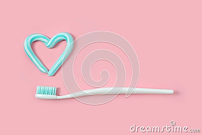 Toothbrushes and turquoise color toothpaste in shape of heart on pink background. Dental and healthcare concept. Stock Photo