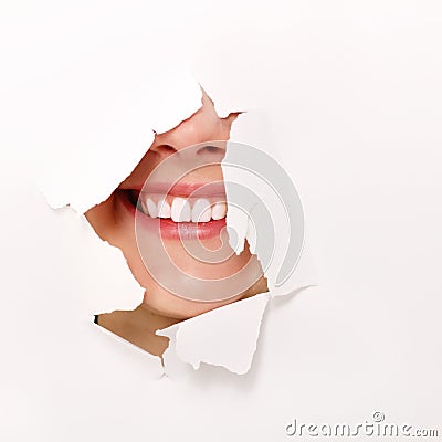 Toothy smile of cheerful teen girl through hole of white Stock Photo