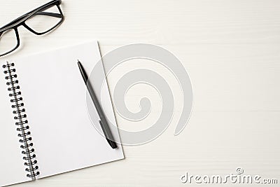 Top above close up flatlay view photo of open clear spiral copybook with black pen and eyewear isolated white wooden backdrop Stock Photo