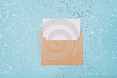 Top above close up view photo of open craft envelope and empty blank white sheet of paper with mock up place on silver confetti Stock Photo