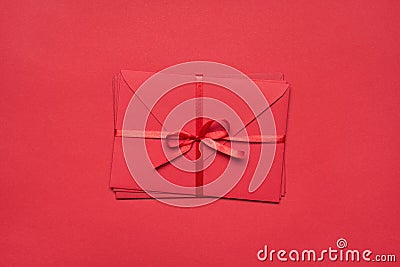 Top above flatlay close up view photo of pile stack of envelopes tied with silky ribbon isolated vivid color red background Stock Photo