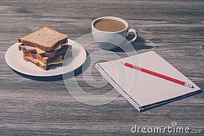 Top above overhead view phot of break rest relax snack at work. Cheese sandwich with cup of white coffee, notebook and pencil. Hor Stock Photo