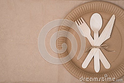 Top above overhead view photo of a set of wooden cutlery lying on a paper plate placed to the right side isolated on craft paper Stock Photo