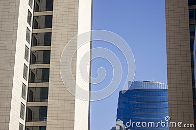 Top of a blue modern corporate high-rise building with a striped design standing in the background between a pair of twin yellowis Stock Photo