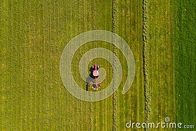 Top down aerial view of a red tractor cultivating farmland with a spinning rack Stock Photo
