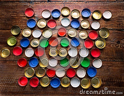 A top-down view of assorted beer caps creating a colorful mosaic-like spread on a wooden surface Stock Photo