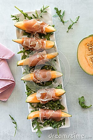 Top down view of cantaloupe wedges wrapped in prosciutto deli meat. Stock Photo