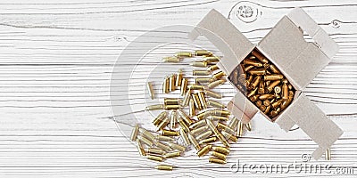 Top down view, carton box with yellow brass ammunition bullets on white wooden desk, banner - space for text left side Stock Photo