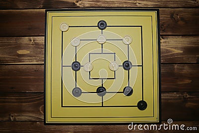 Top down view on gameboard with black and white pieces of strategy game for two people - nine men`s morris or mills Editorial Stock Photo